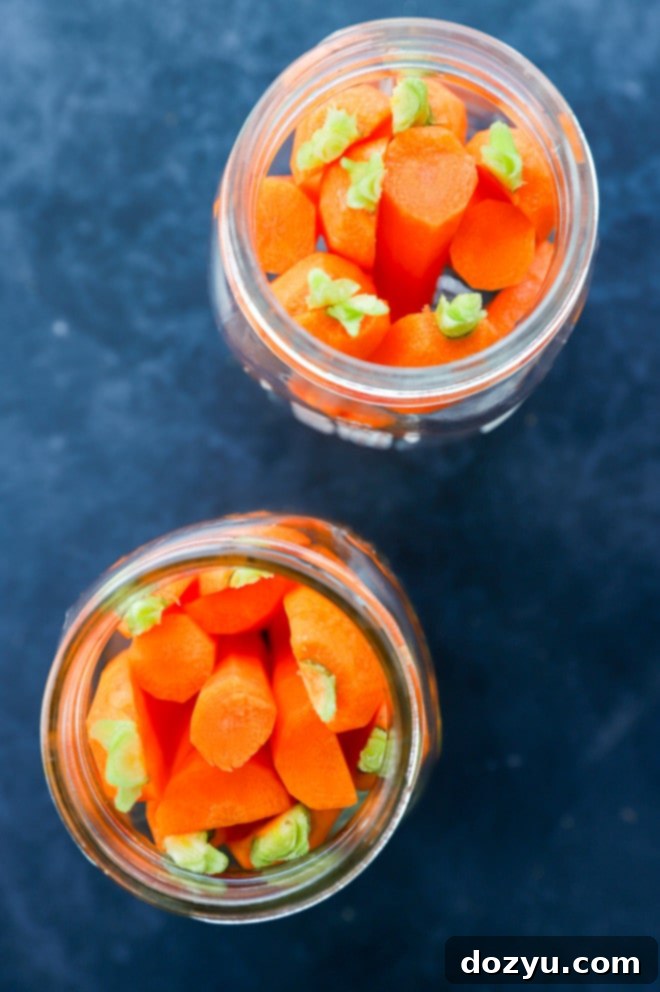 Zesty Quick-Pickled Carrots 3 Assortment of vibrant vegetables, including carrots, submerged in clear pickling liquid within glass jars, ready for storage.