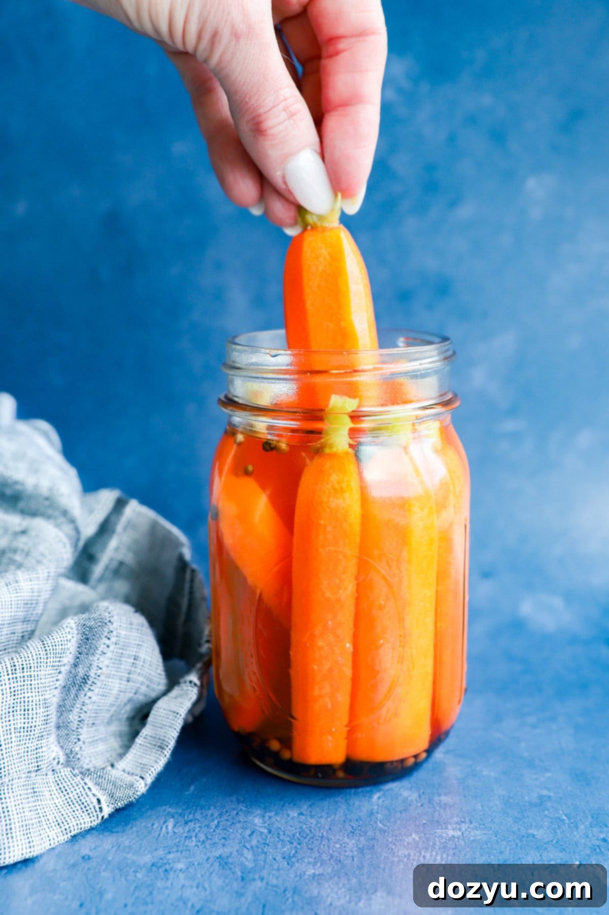 hand pulling out a quick pickled carrot from a jar