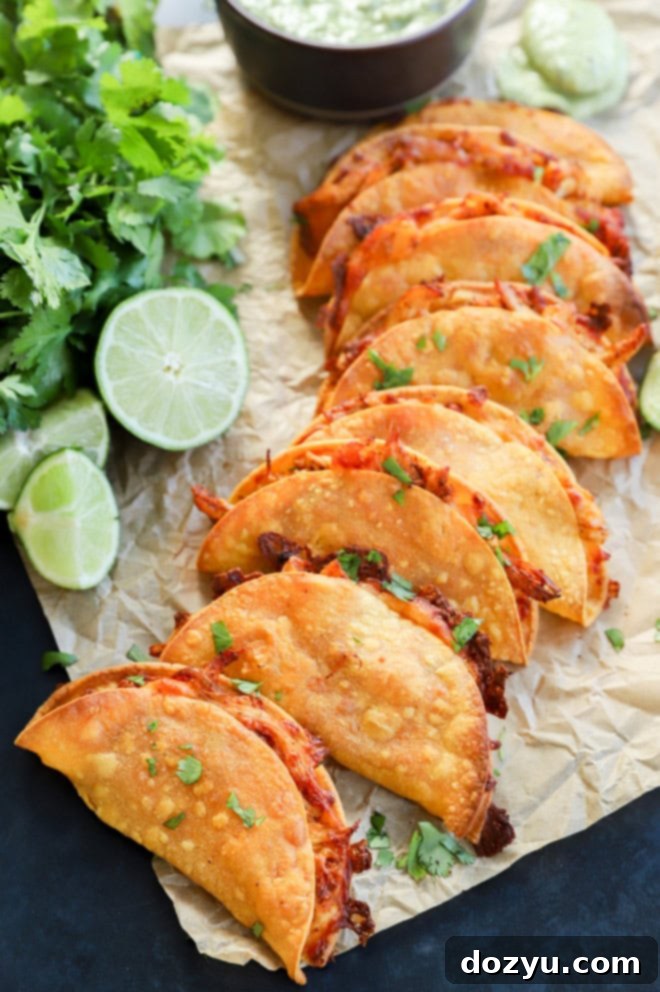 Crispy baked chicken tacos served on parchment paper with a side of creamy avocado tomatillo salsa