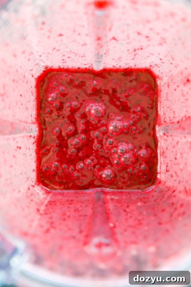 Homemade blueberry sauce being blended in a high-speed blender for a smooth margarita base.