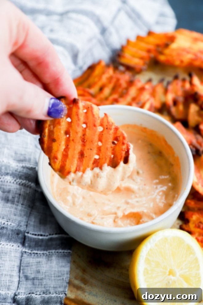 Hand holding fry dipped into a creamy sauce