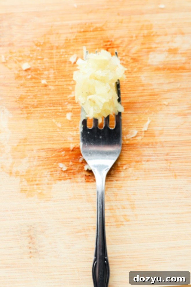 mashed garlic on a fork on a cutting board