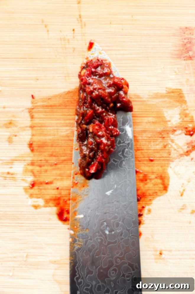 chopped chipotle peppers on a knife on a cutting board