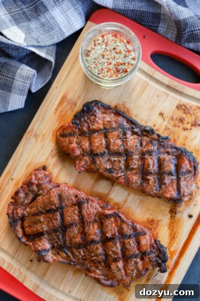 Perfectly Grilled New York Strip 3 new york strip steaks on cutting board with steak rub and crosshatch grill marks