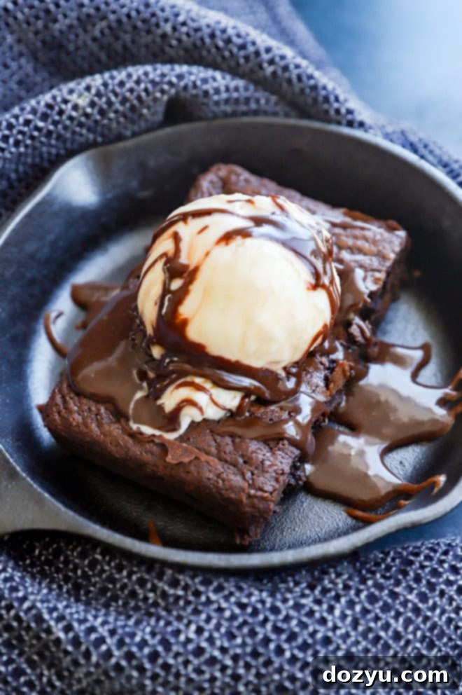 Homemade baked chocolate brownie served hot on a sizzling skillet with a generous scoop of vanilla ice cream and rich chocolate sauce.