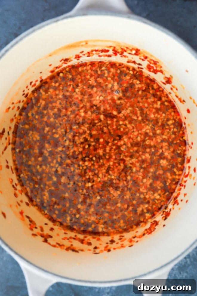 red pepper flakes and hot sauce in sweet liquid in a saucepan