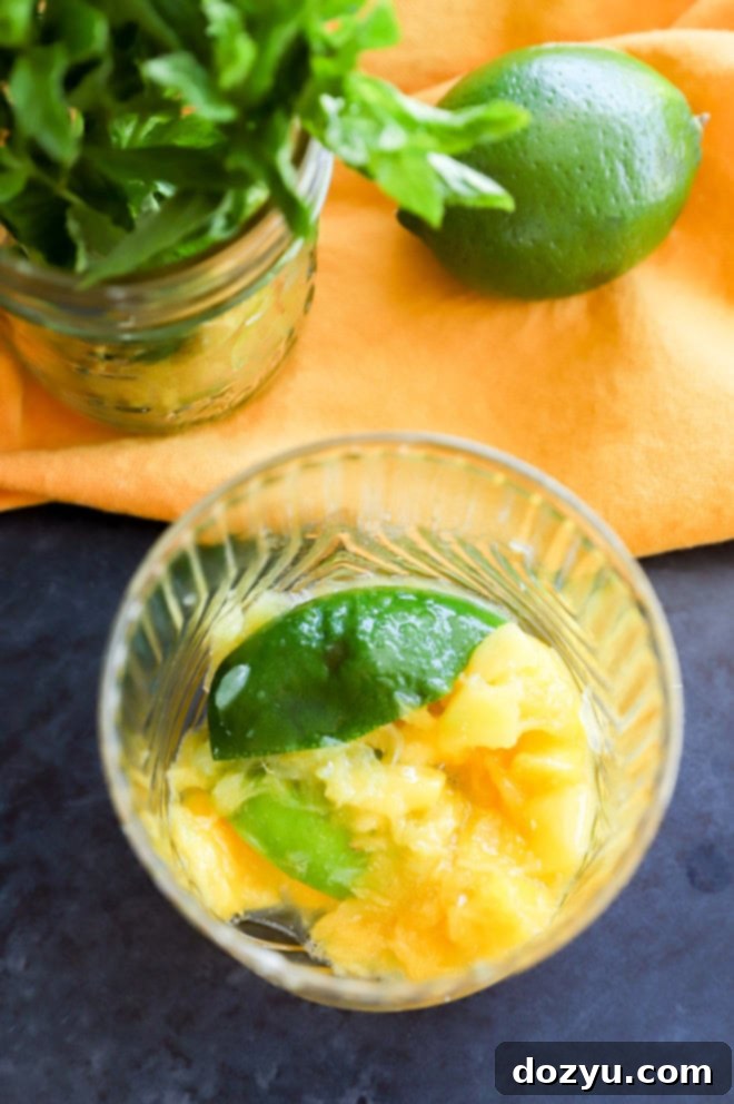 Tropical Mango Mojito 5 Muddled mango and lime at the bottom of a glass, highlighting the initial flavor base of the mojito.