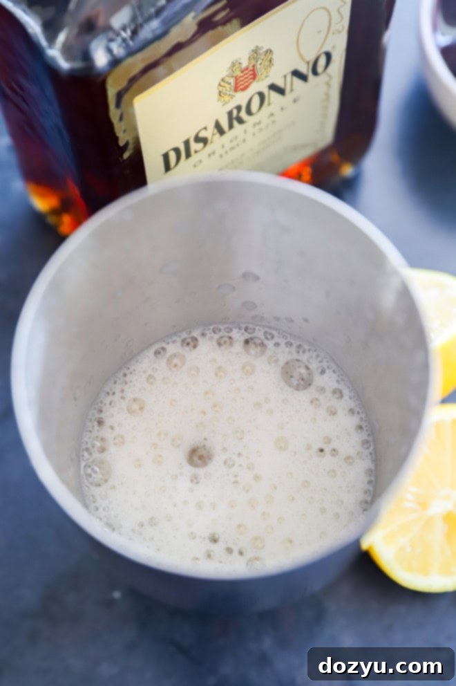 Shaken with ice disaronno sour with disaronno bottle in the background