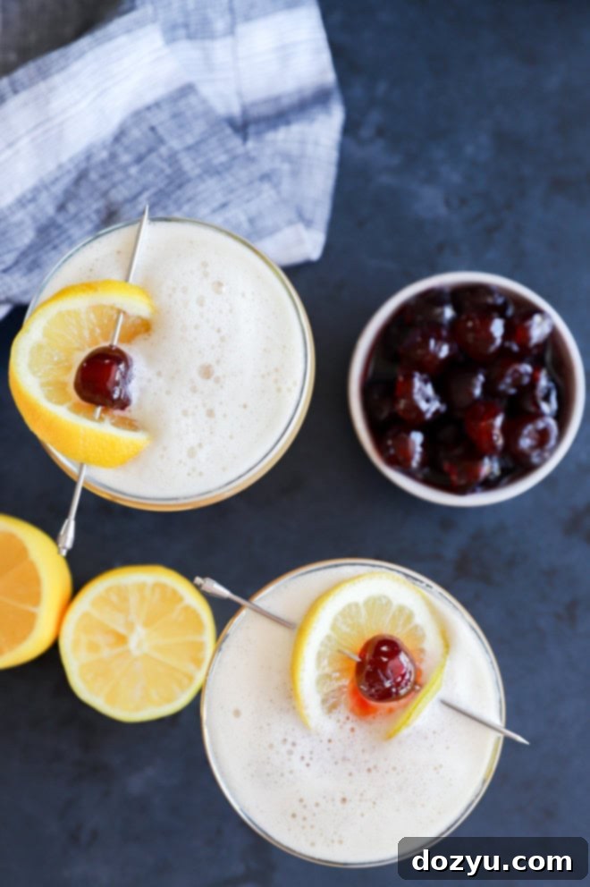 Glasses with amaretto sour cocktail with lemon and cherry garnish
