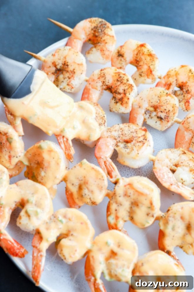 Brushing bang bang sauce onto grilled shrimp skewers