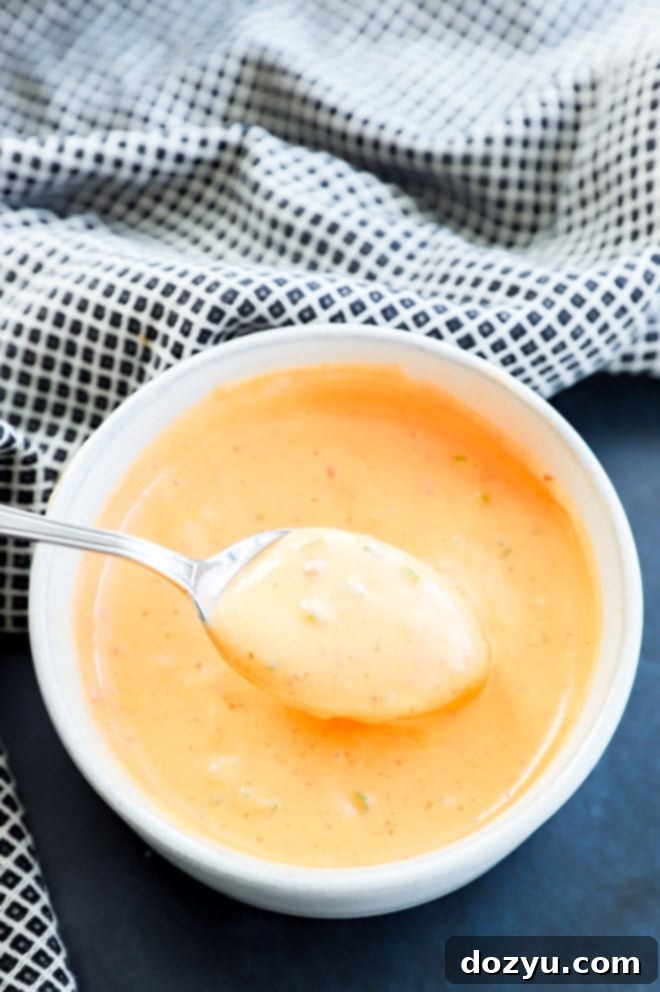 Spoon lifting out bang bang shrimp sauce of a bowl