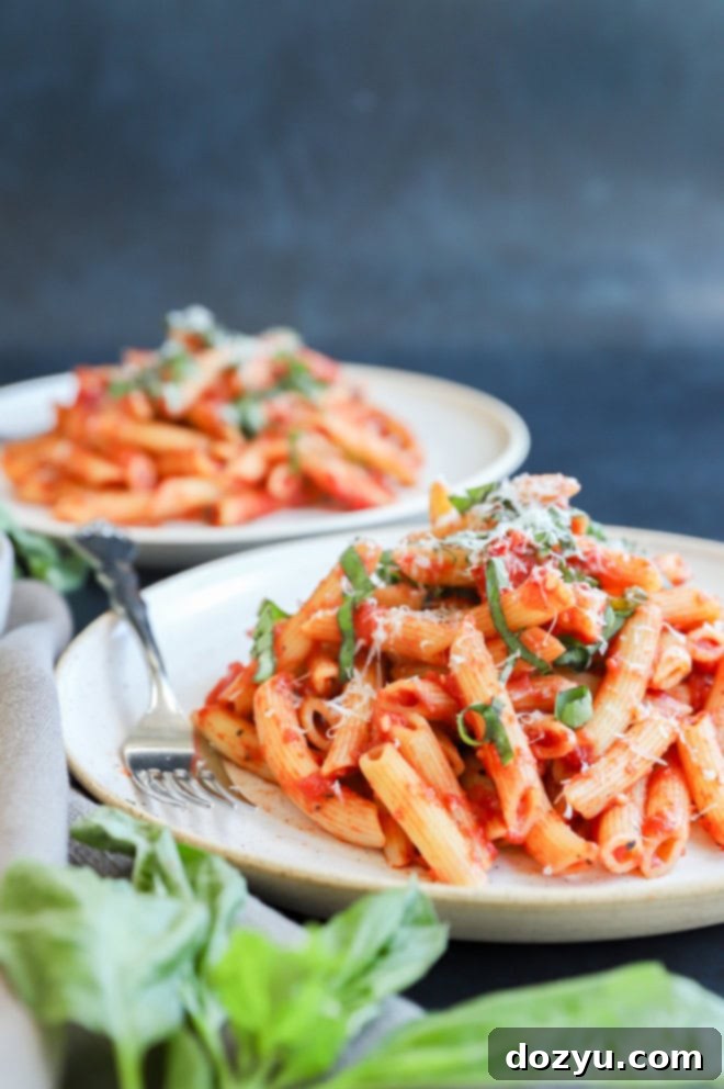 Penne pomodoro on plate with fresh basil on top and cheese