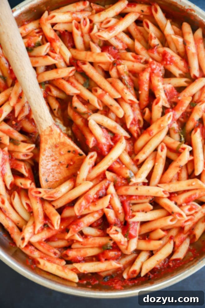 Fresh penne pomodoro pasta in a skillet with basil garnish