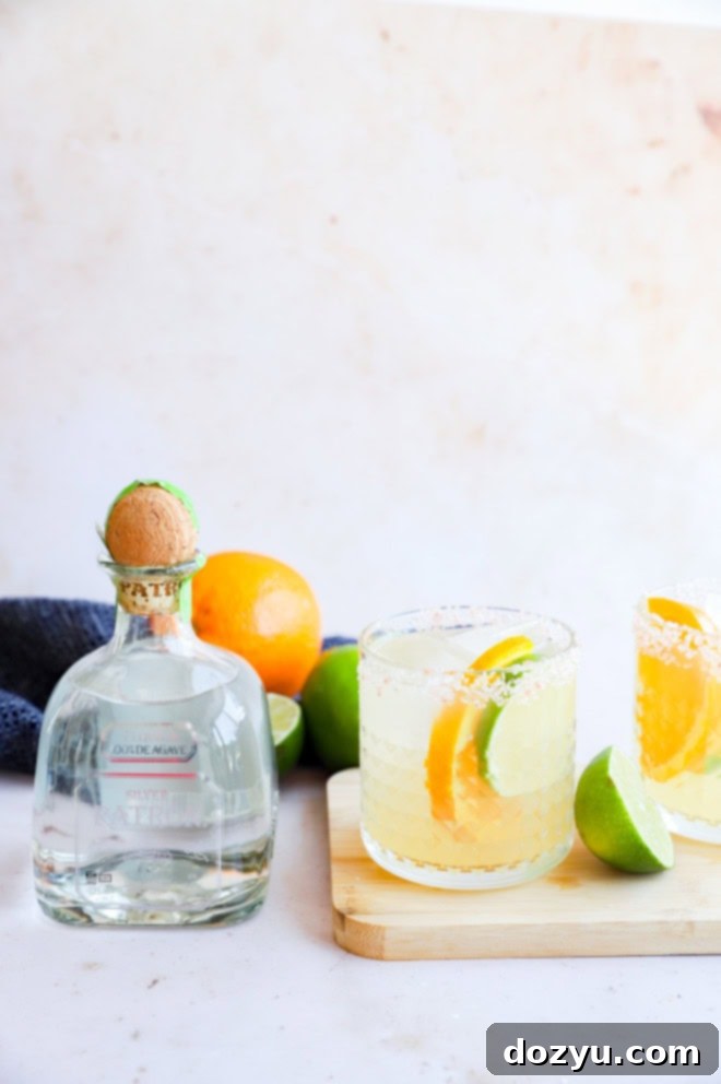 Patron Silver tequila bottle next to a single margarita in a salt-rimmed glass, ready to be enjoyed