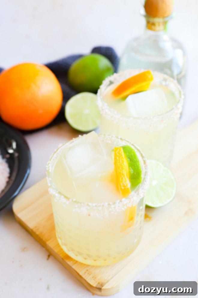 Two Patron margaritas in salt-rimmed glasses, garnished with citrus, against a soft background