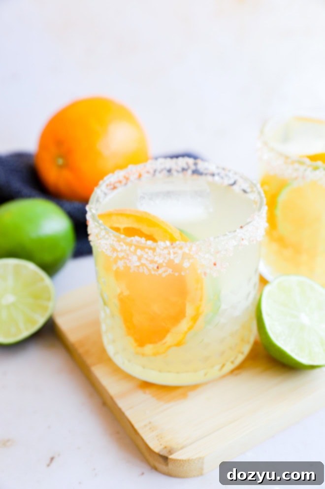 Assortment of fresh orange slices and lime halves arranged with tequila cocktails in glasses