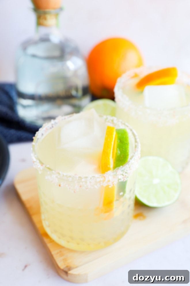Two vibrant Patron margaritas in elegant glasses, with a Patron tequila bottle prominently featured in the soft-focus background