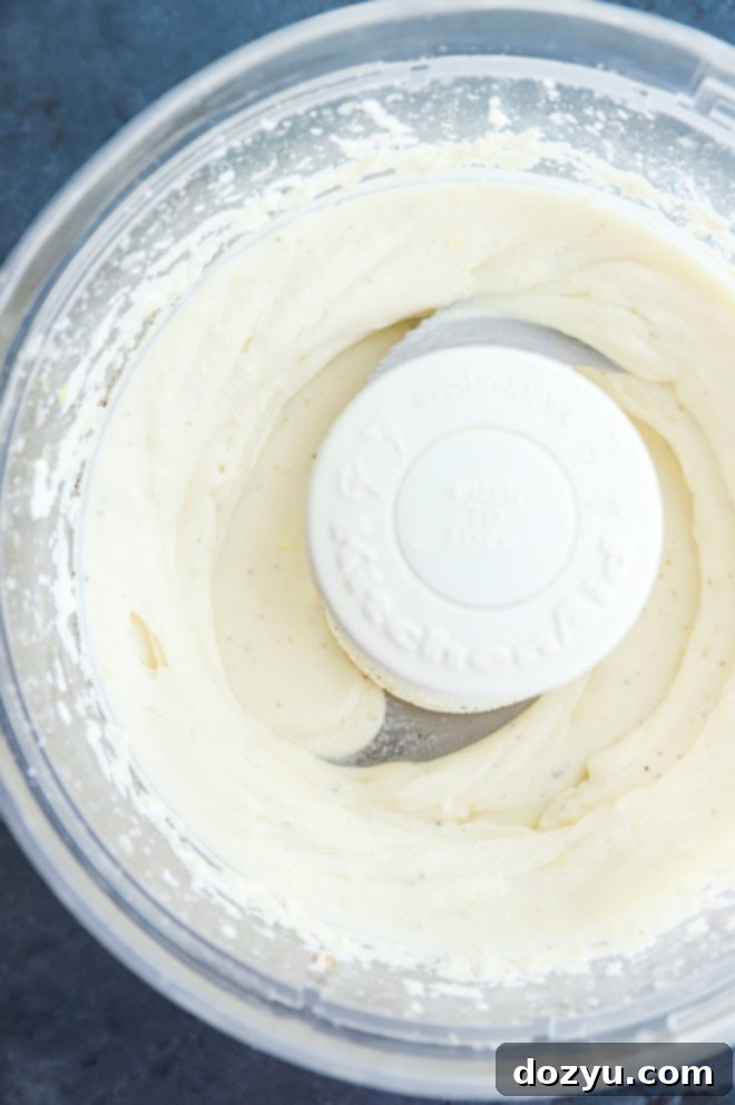 Close-up of fluffy whipped ricotta being prepared in a food processor, highlighting its smooth texture.