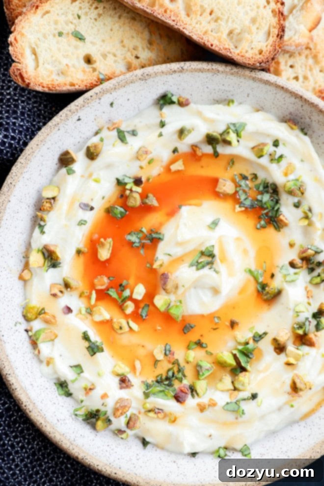 A bowl of creamy whipped ricotta, generously drizzled with honey and served alongside golden toasted bread slices.