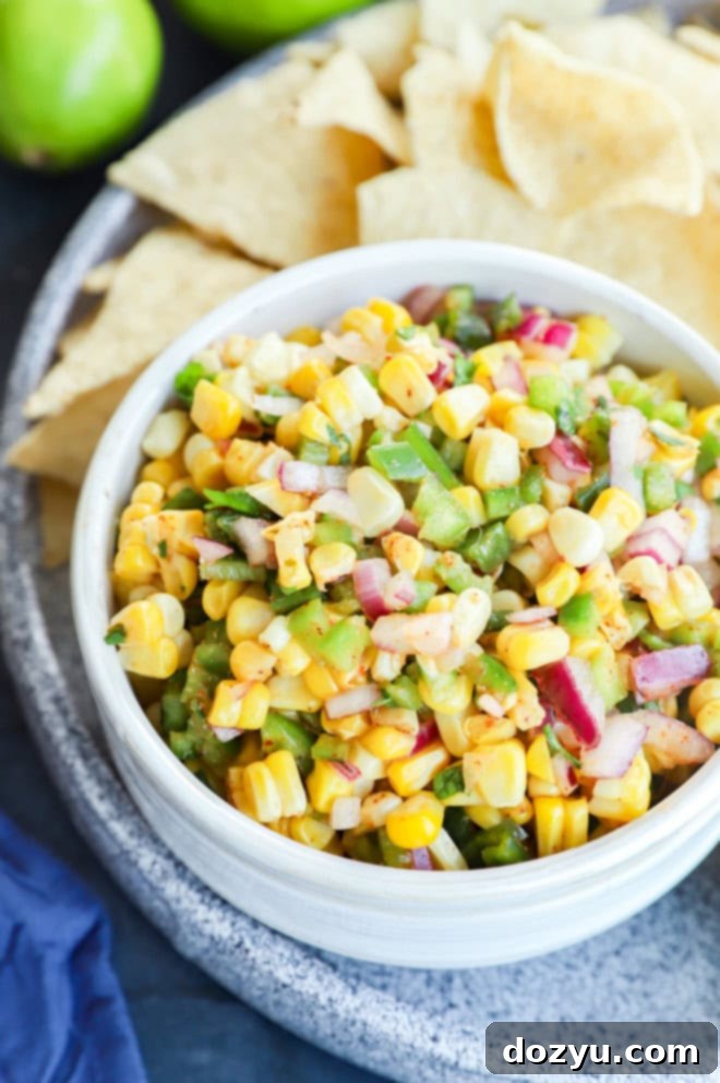 small bowl of roasted chili corn salsa with tortilla chips and limes