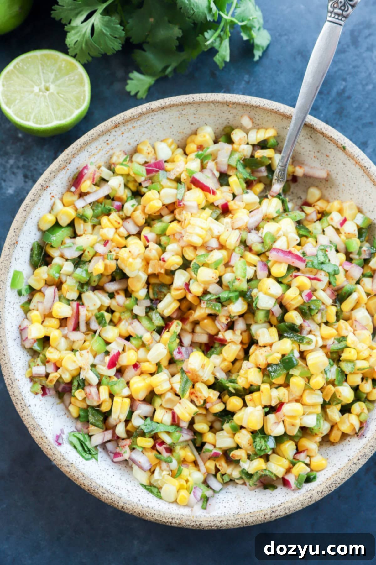roasted chili corn salsa in a bowl with a lime and cilantro