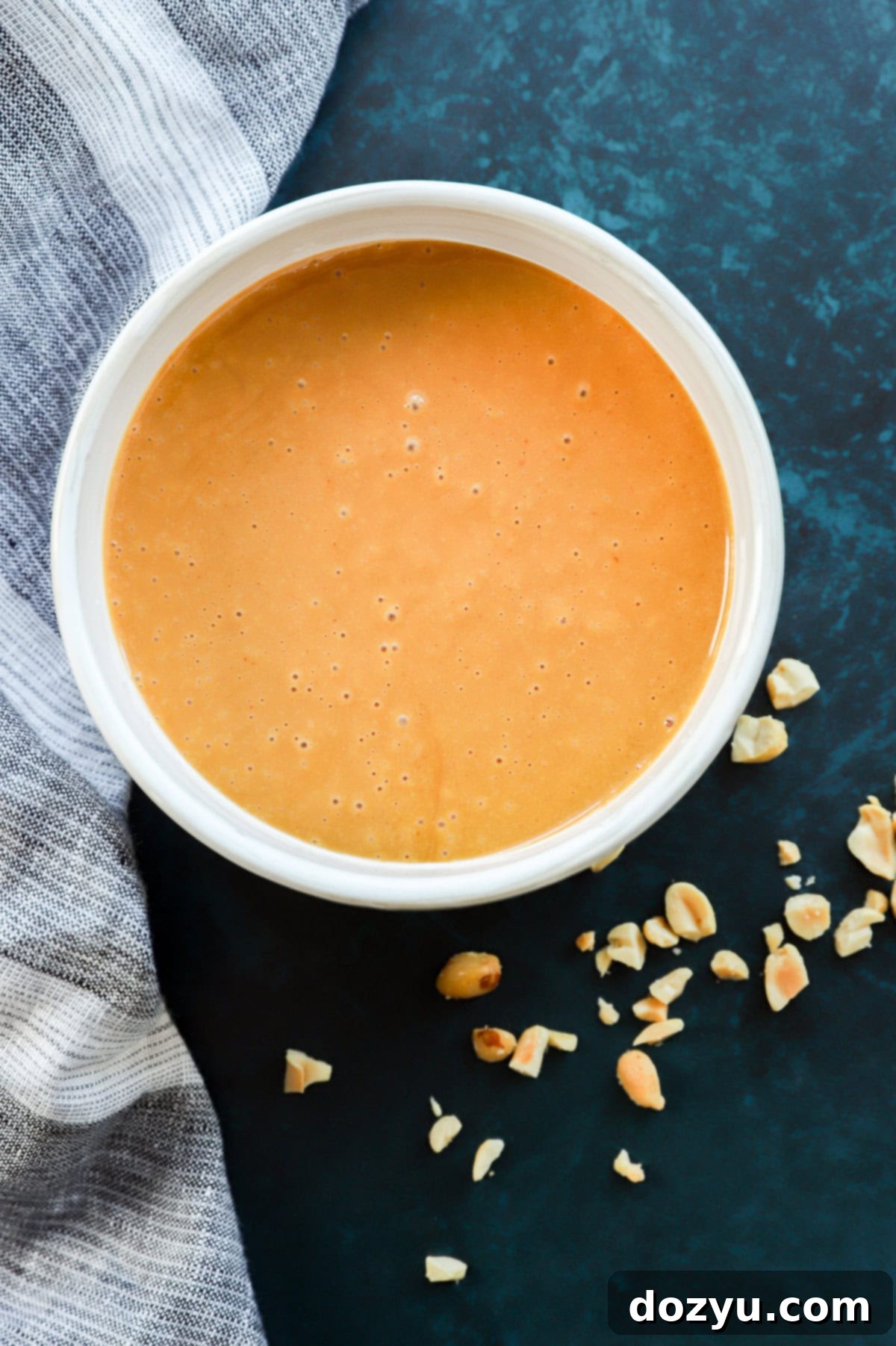 Creamy Thai Peanut Dressing 9 thai peanut salad dressing in a bowl with chopped peanuts around it