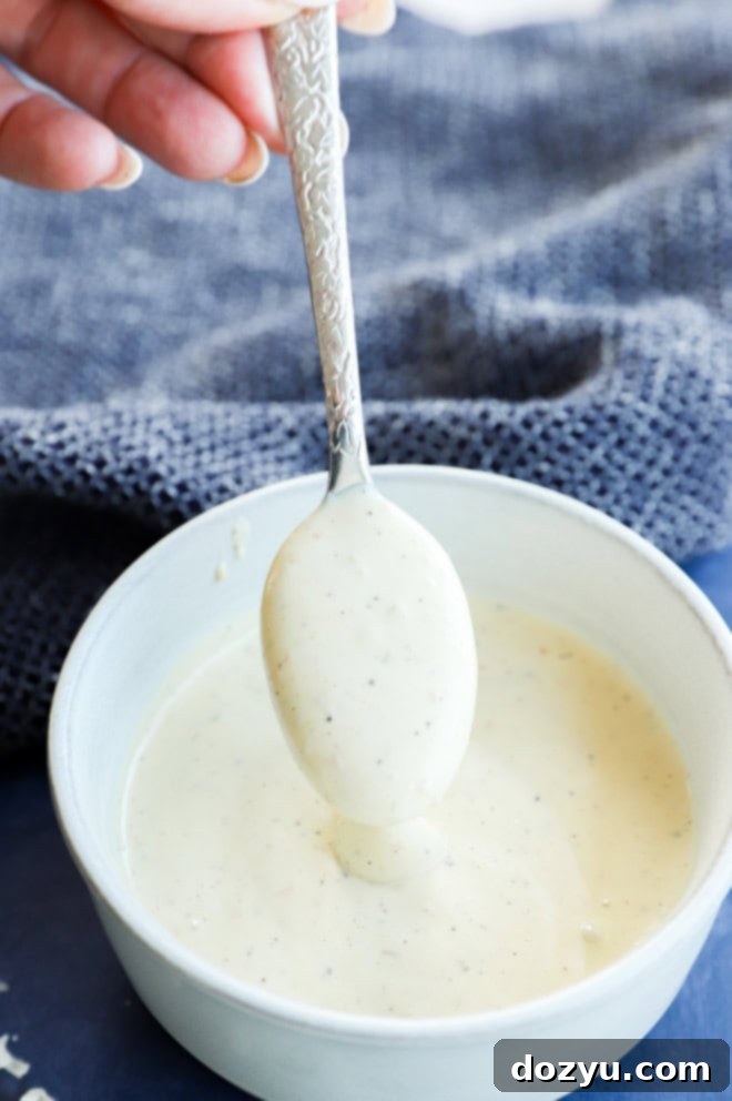 spoonful of creamy salad sauce in a bowl, showcasing the rich texture of homemade Caesar dressing