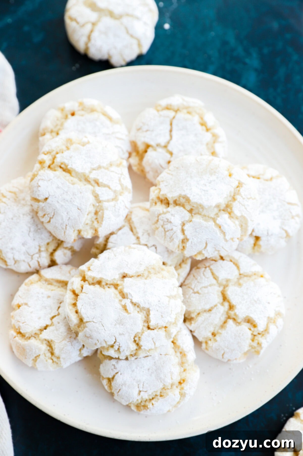 pretty cracked amaretti cookies on plate with linen and green countertop