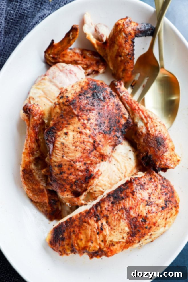 whole grilled chicken on platter in pieces with serving utensils