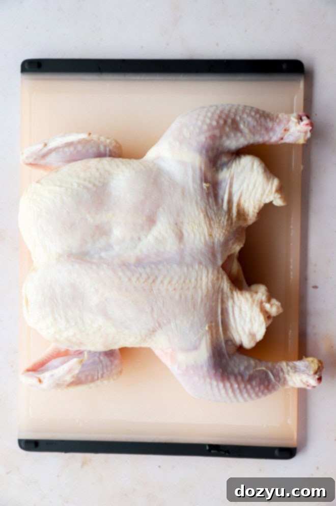 spatchcocked raw chicken on cutting board