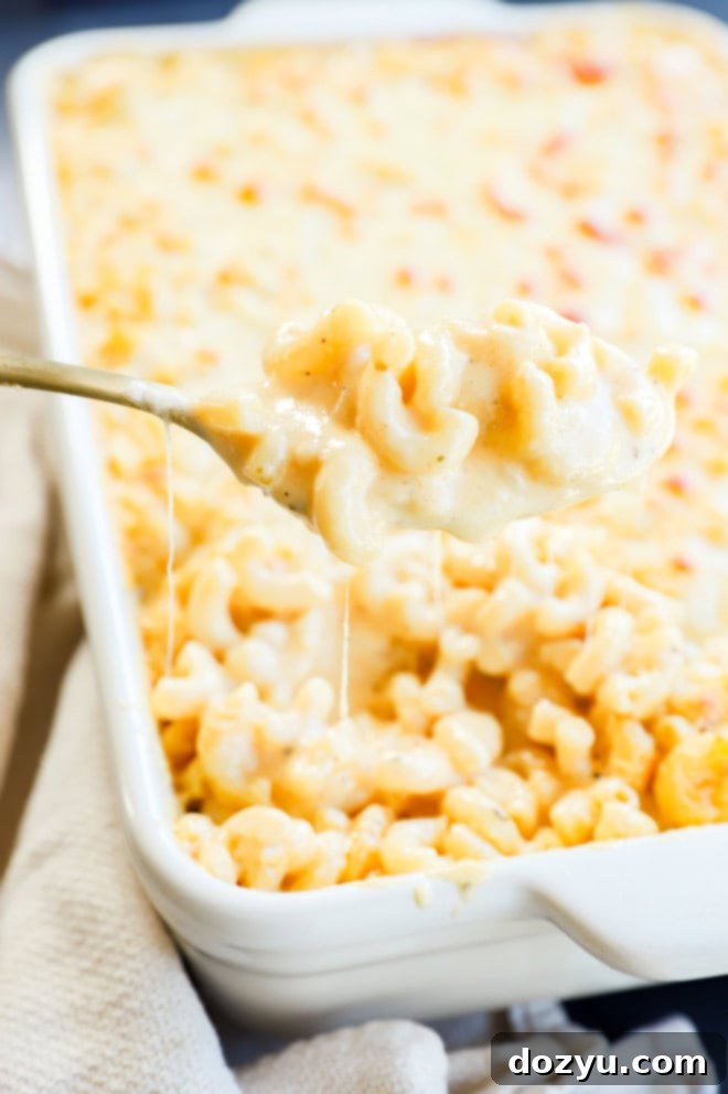 A spoonful of incredibly creamy and cheesy macaroni and cheese being lifted from a baking dish, showcasing its perfect texture.