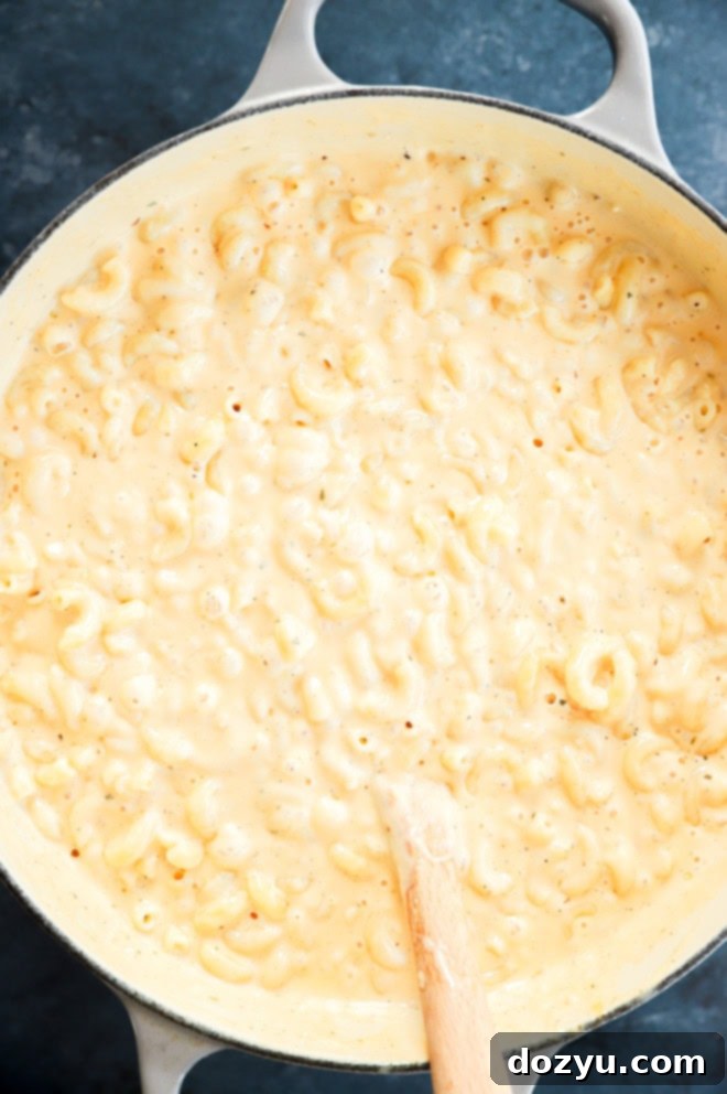Large pot filled with creamy, unbaked four cheese mac and cheese, ready to be transferred to a baking dish.