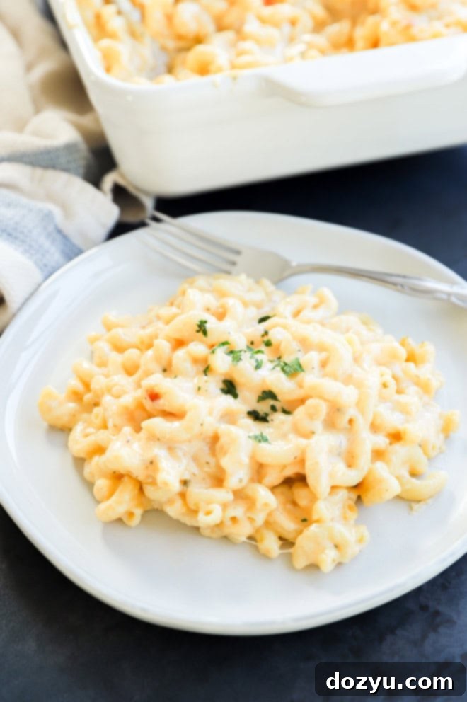 A plate of four cheese mac and cheese garnished with fresh chopped parsley, highlighting its creamy texture.