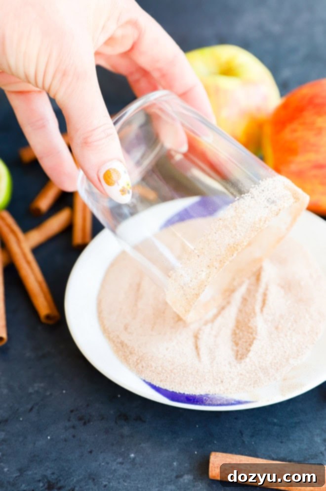The process of preparing a cinnamon sugar rim, showcasing a glass being rolled through the sweet and spicy mixture on a plate.