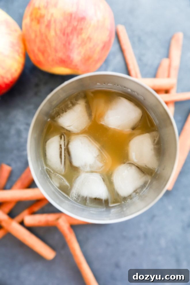 An apple cider margarita chilling in a cocktail shaker filled with ice, ready to be poured.