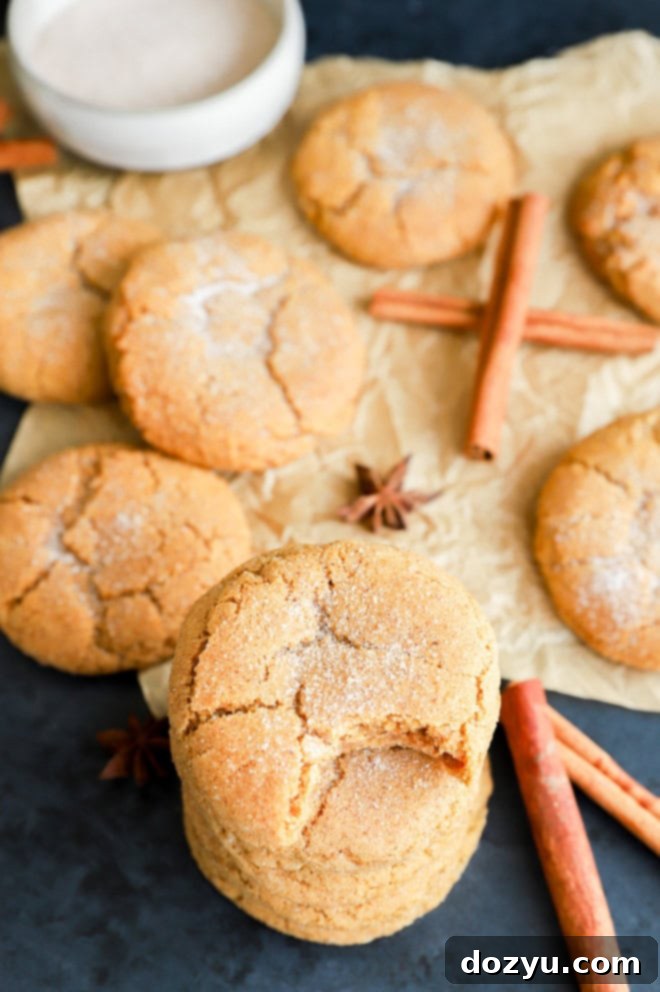 A tall stack of enticing fall cookies, generously coated with cinnamon sugar, accompanied by aromatic cinnamon sticks.