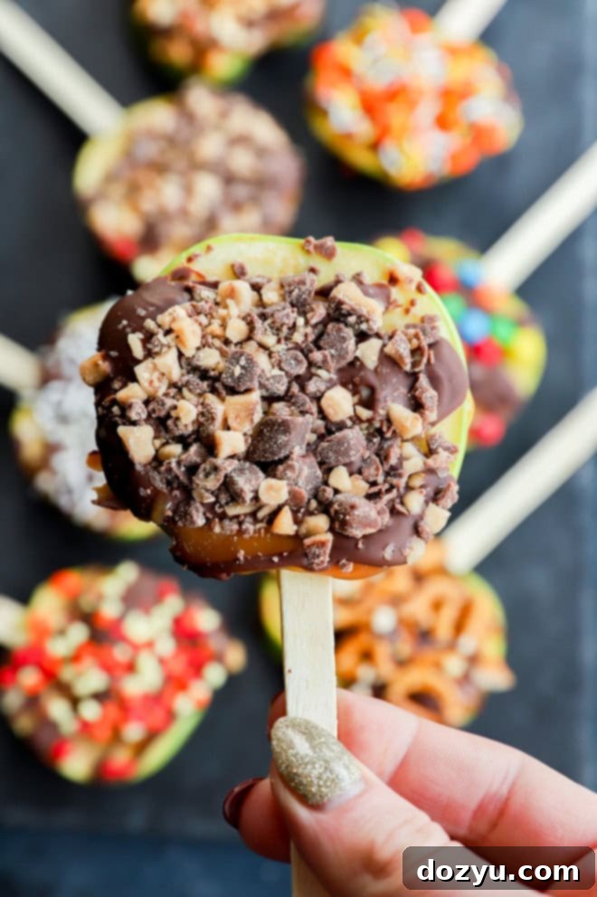 Hand holding a candy apple slice topped with toffee bits