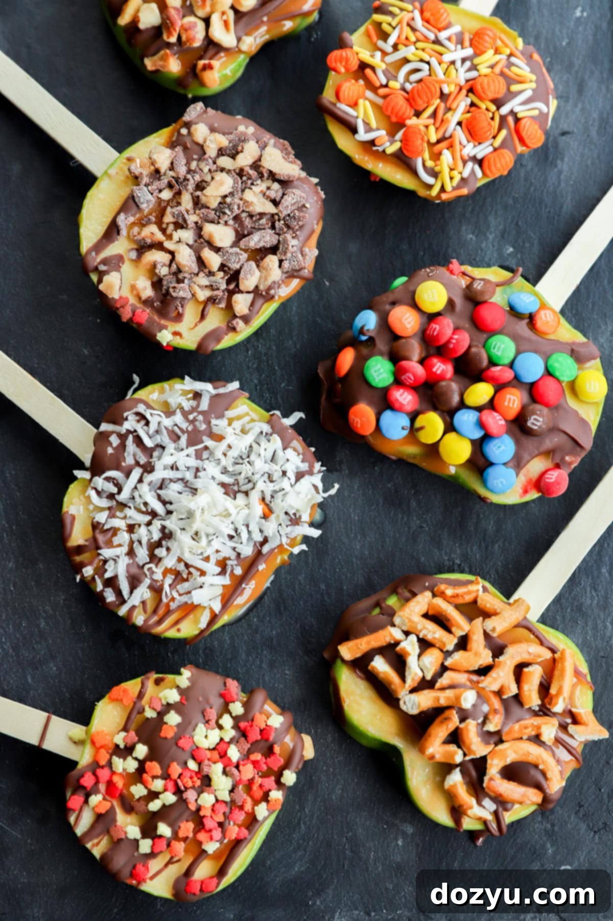 Line of sliced apples adorned with chocolate, caramel, and various toppings