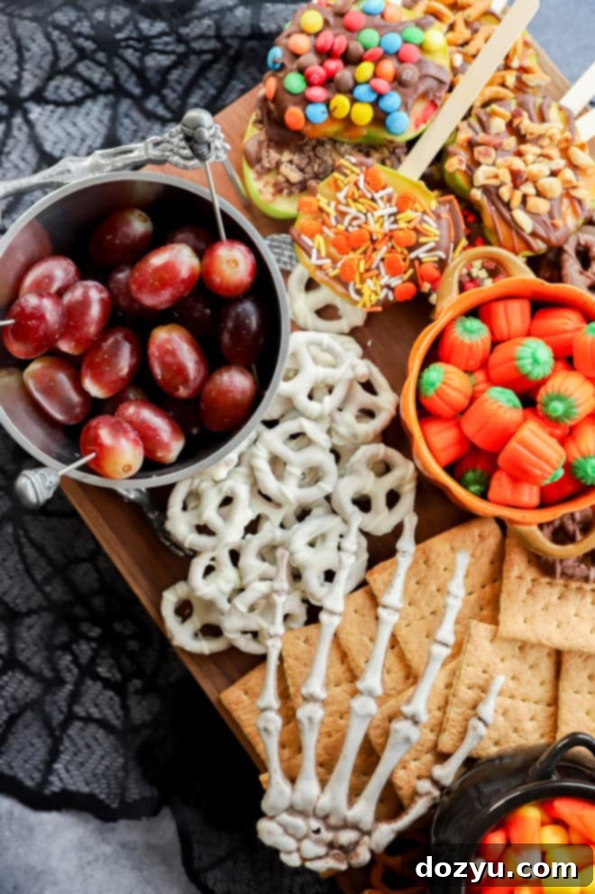 A playful skeleton hand reaching for graham crackers on a spooky Halloween dessert charcuterie board, amidst a vibrant collection of treats.