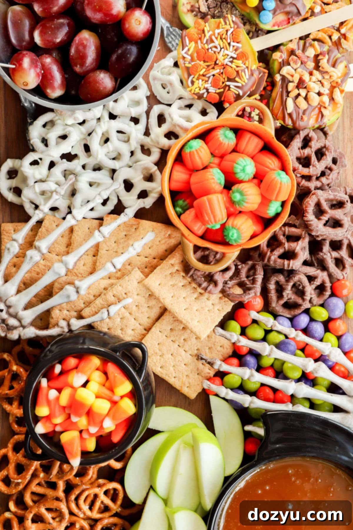 skeleton hands on a sweet treat platter with candies, fruits, and crackers