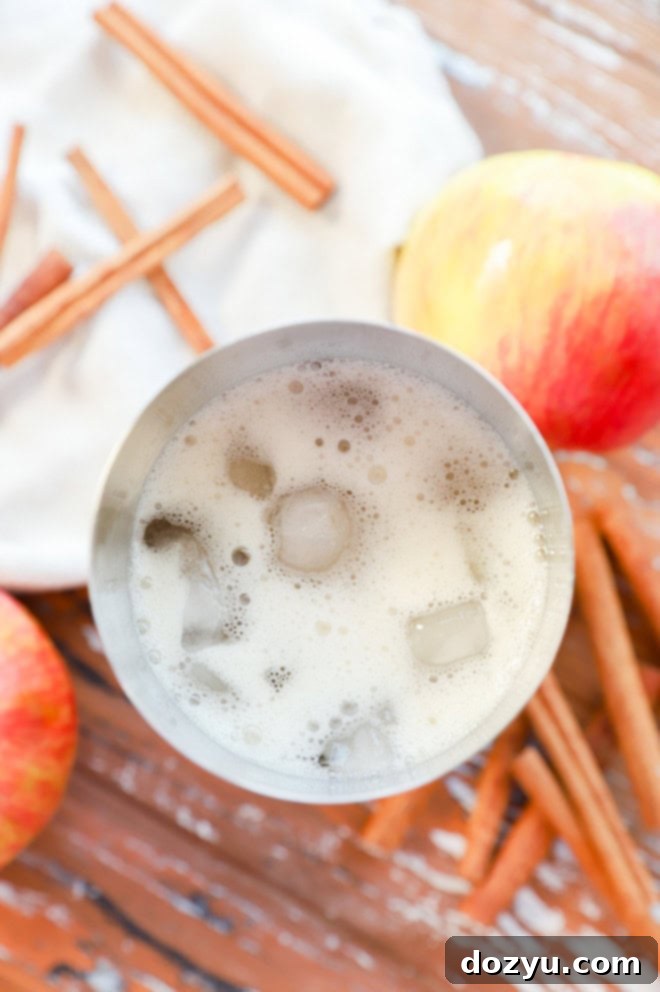 making an apple cider cocktail in a shaker filled with ice