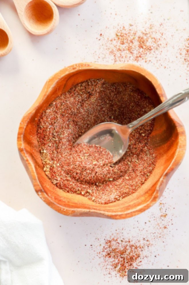 Make Your Own Chili Seasoning Mix 2 A rustic bowl filled with rich homemade chili seasoning, a spoon resting inside, with measuring spoons in the background, highlighting the fresh, vibrant spices.