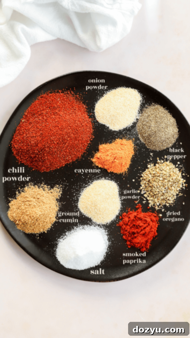 Make Your Own Chili Seasoning Mix 3 A beautifully arranged plate displaying nine essential ingredients for homemade chili seasoning, each clearly labeled: chili powder, cumin, salt, paprika, oregano, pepper, garlic powder, onion powder, and cayenne pepper.