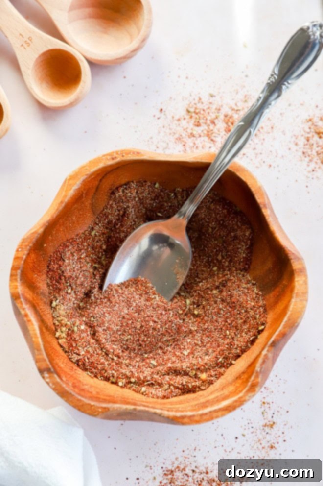Make Your Own Chili Seasoning Mix 7 A ceramic bowl brimming with homemade spice mixture, accompanied by a wooden spoon, suggesting a comforting and flavorful culinary experience.