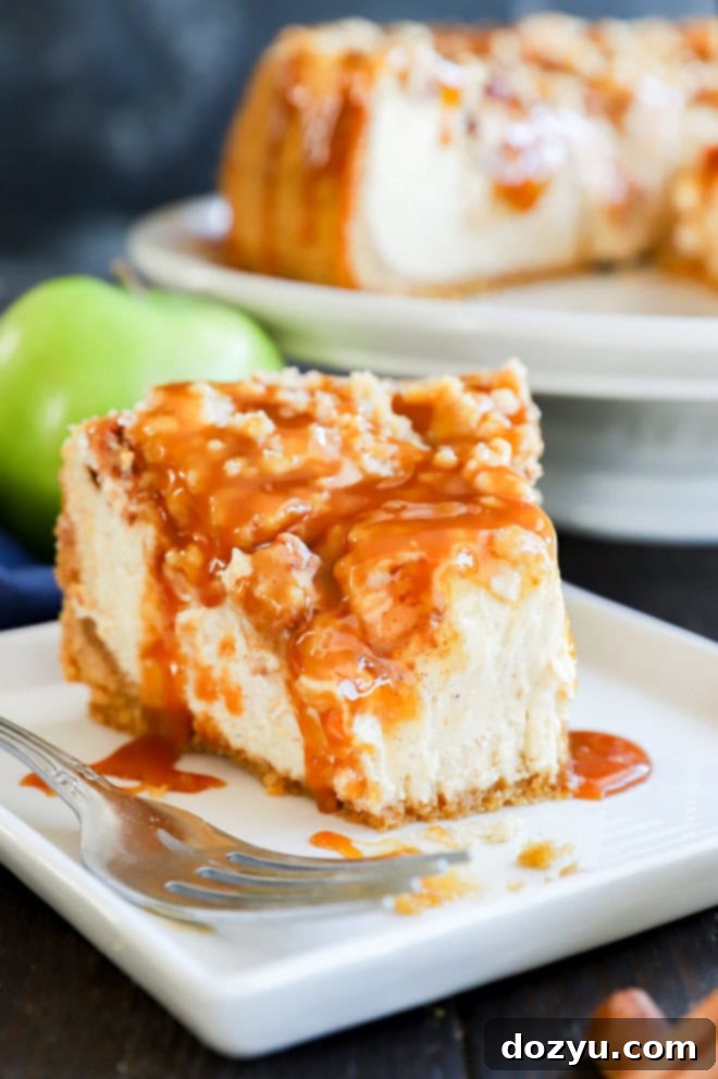 A close-up shot of a slice of Caramel Apple Crumble Cheesecake on a plate, with a fork having taken a bite, highlighting the rich, layered interior and tempting texture.