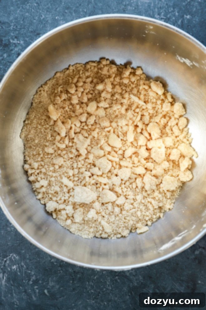 Close-up of buttery crumble topping in a bowl on a kitchen counter, showcasing its coarse texture ready for baking.