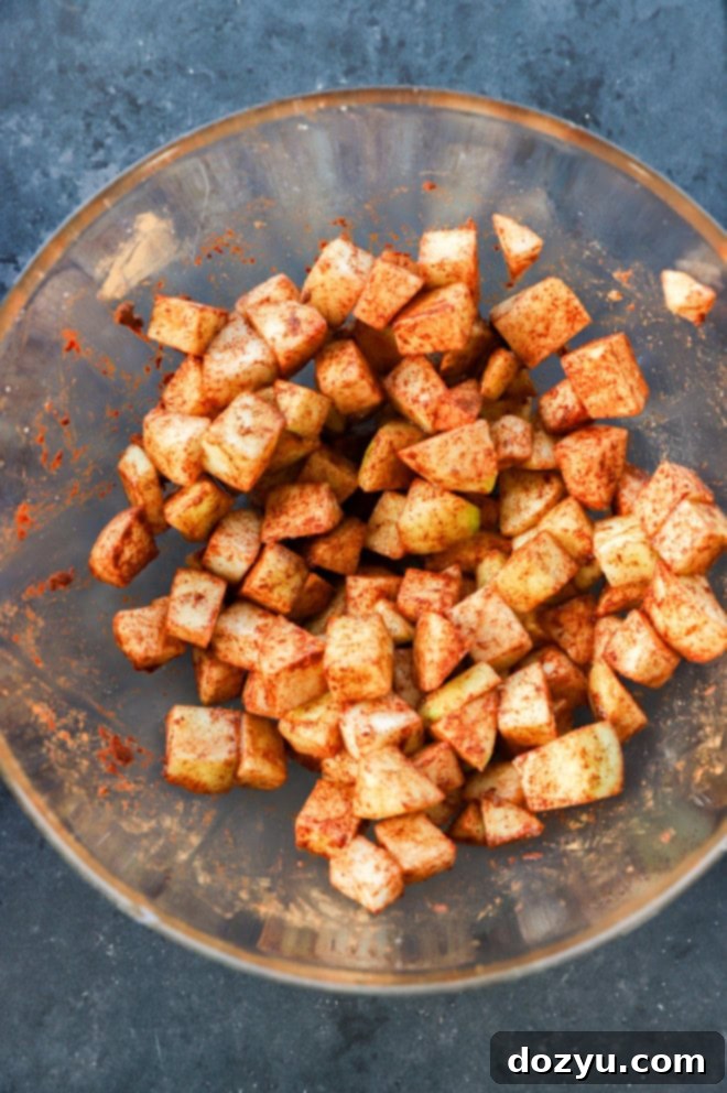 Bowl of freshly chopped, cinnamon-spiced apples ready to be layered into the cheesecake, sitting on a kitchen counter.