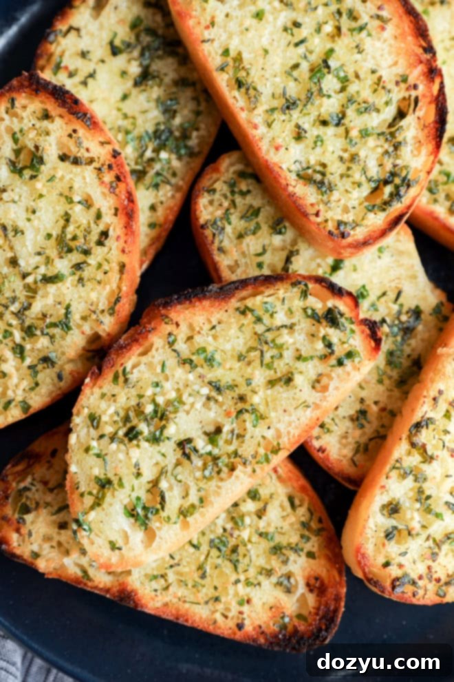 Crispy sourdough garlic toast slices on a plate with fresh herbs and butter