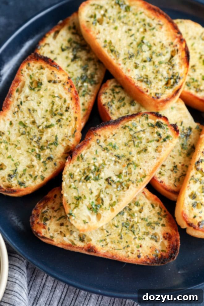 A stack of golden-brown sourdough garlic toast slices on a plate