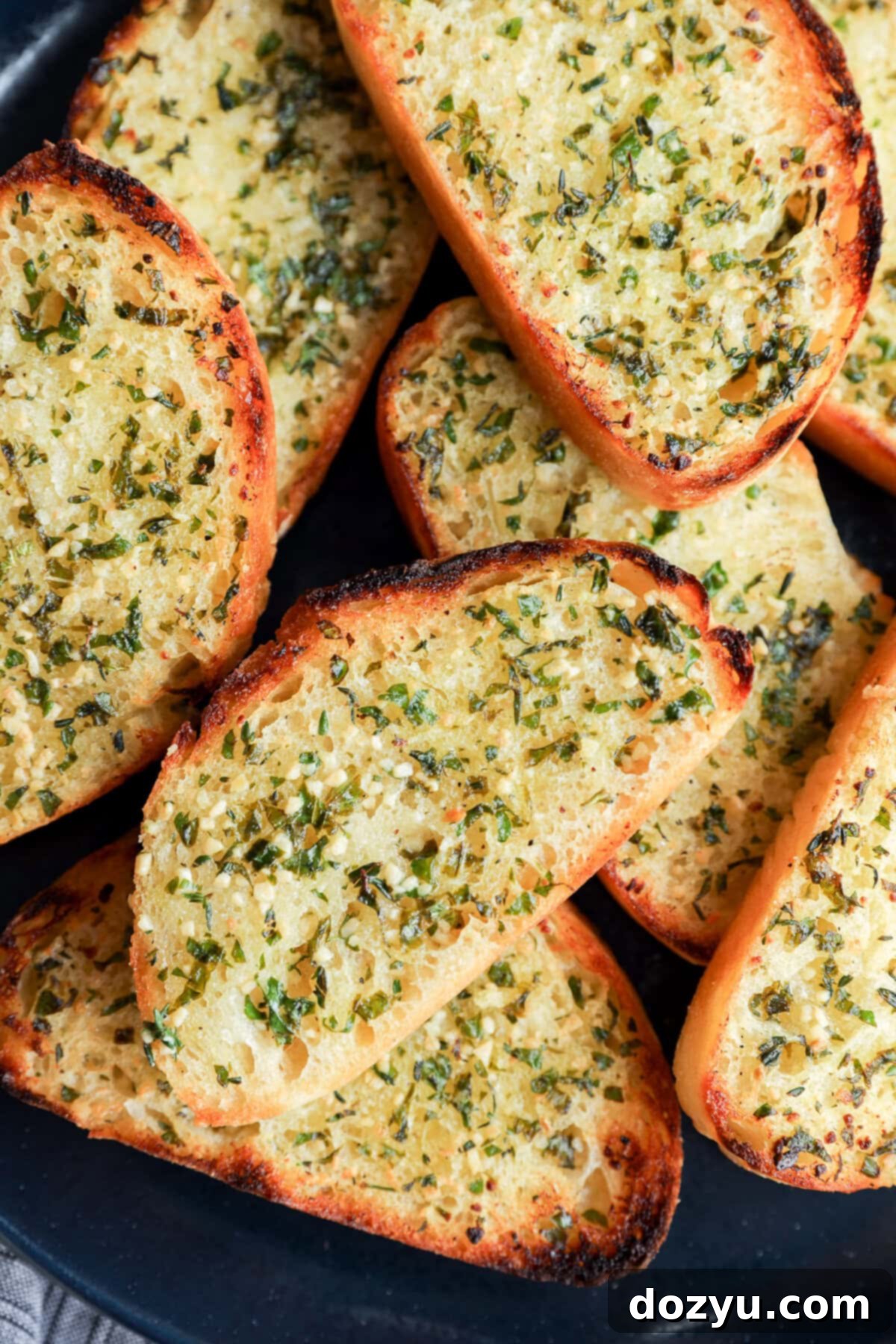 Crispy sourdough garlic toast slices on a plate with fresh herbs and butter